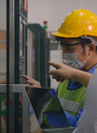 Asian factory worker man operating automated programming CNC milling control machine industry center at tool workshop manufacturing with engineer man also discuss together